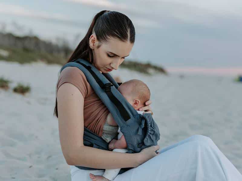 mamá amantando a su bebé en el portabebés para que no llore