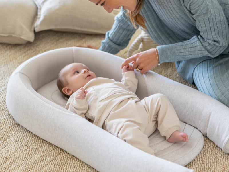 mama sonriendo a su bebé mientras descansa a su lado 