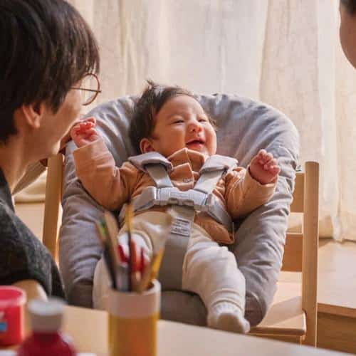 padres sonriendo a su bebé en la mesa en la trona Stokke Tripp Trapp de recién nacido