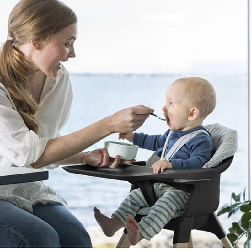 mamá dando de comer a su bebé en la Stokke Clikk con bandeja