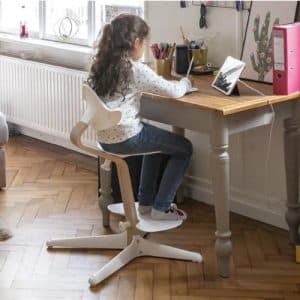 imagen en la que se aprecia el diseño ergonómico de la silla Stokke Nomi con una niña estudiando