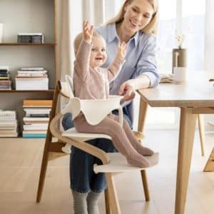 niña sentada en una Nomi apoyando correctamente los pies y espalda gracias a su diseño ergonómico