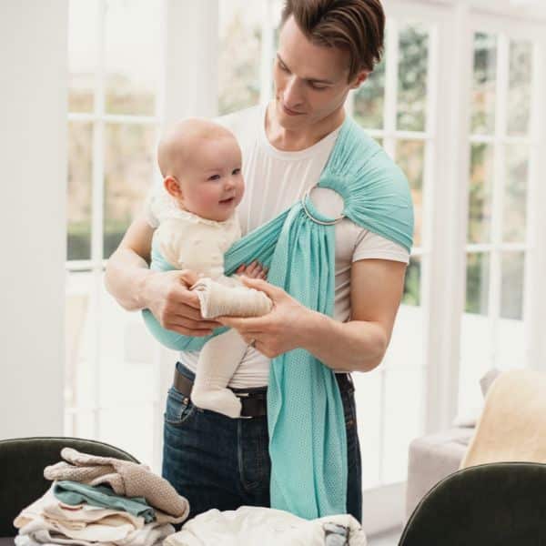 papa realizando las tareas con un portabebés ergonómico en el que se aprecia en detalle la ergonomía en el porteo sin dolor