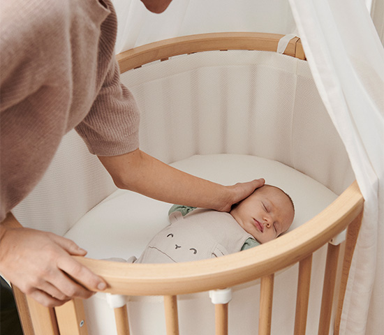 imagen de una mam&aacute; besando a su beb&eacute; en lacuna ovalada para beb&eacute; Stokke 