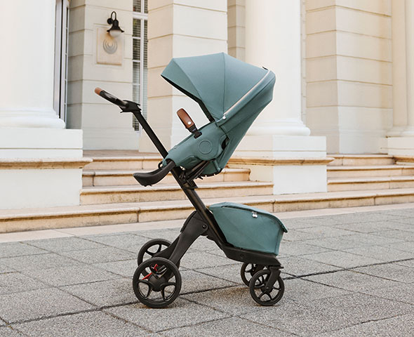 mujer paseando un carrito de Stokke elegante en entorno urbano