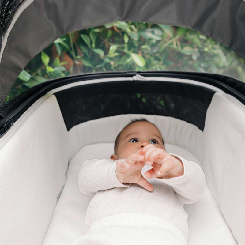 Bebé tumbado en el interior del capazo UPPAbaby Vista V2 con colchón ergonómico y capota extendida