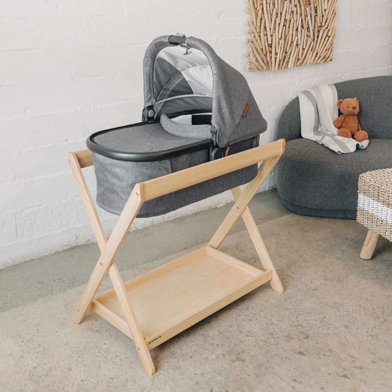 Capazo UPPAbaby colocado sobre soporte de madera tipo minicuna en habitación infantil acogedora